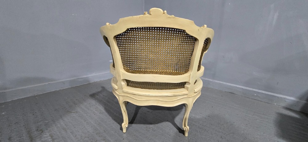 A French Louis XV style cream painted and gilded tub armchair featuring a carved wooden frame with hand-woven rattan cane back, sides, and seat on cabriole legs. View VI