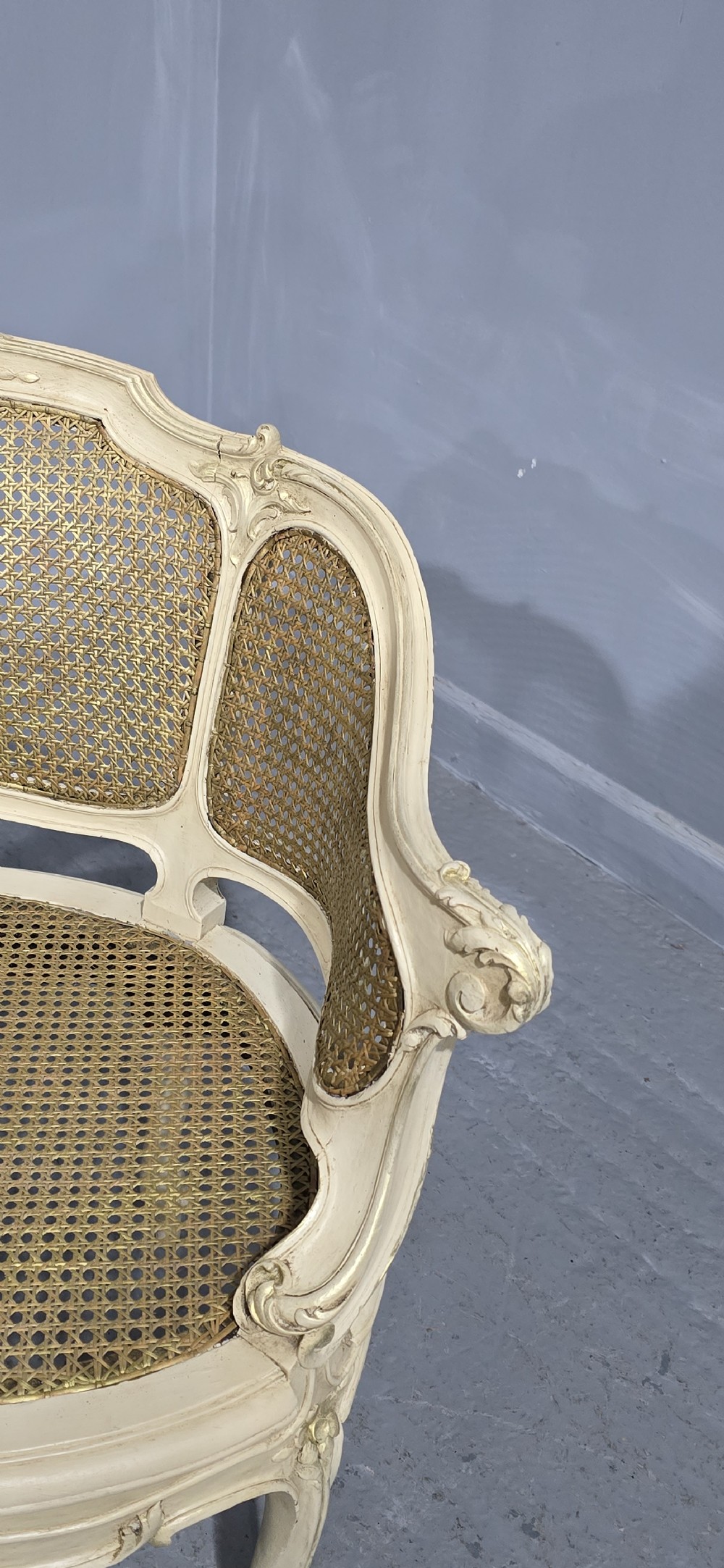 A French Louis XV style cream painted and gilded tub armchair featuring a carved wooden frame with hand-woven rattan cane back, sides, and seat on cabriole legs. View XII