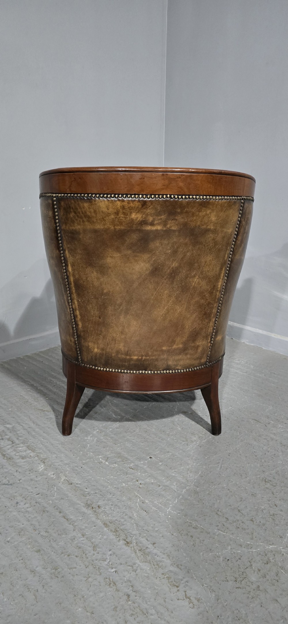 A Regency mahogany library armchair upholstered in aged tan leather featuring carved scroll arms, brass studding, and carved paw feet. View XIII