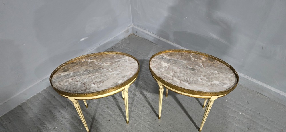 A pair of oval cream-painted French side tables featuring grey-veined marble tops, pierced brass galleries, and fluted tapered legs. View III