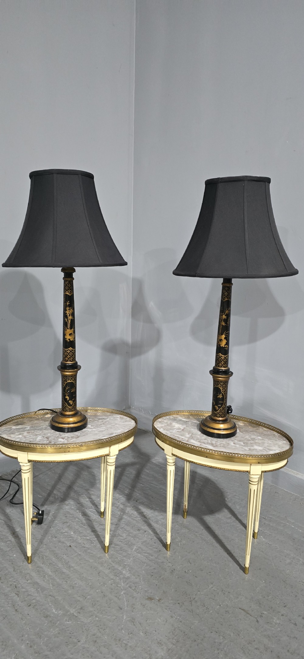A pair of tall black lacquered table lamps featuring hand-painted gold Chinoiserie motifs and topped with black fabric shades. View II