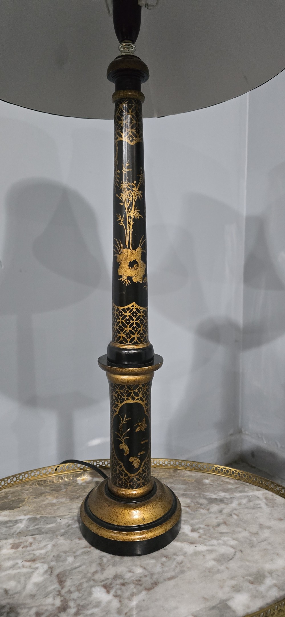 A pair of tall black lacquered table lamps featuring hand-painted gold Chinoiserie motifs and topped with black fabric shades. View V
