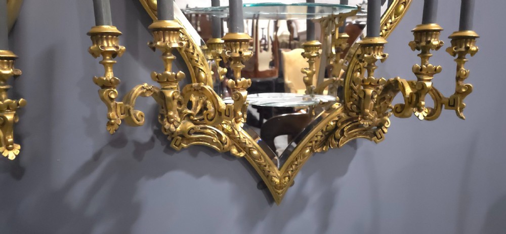 A pair of shaped giltwood girandole wall mirrors featuring ornate carved frames, integrated glass shelves, and multi-branch candle sconces. View IX