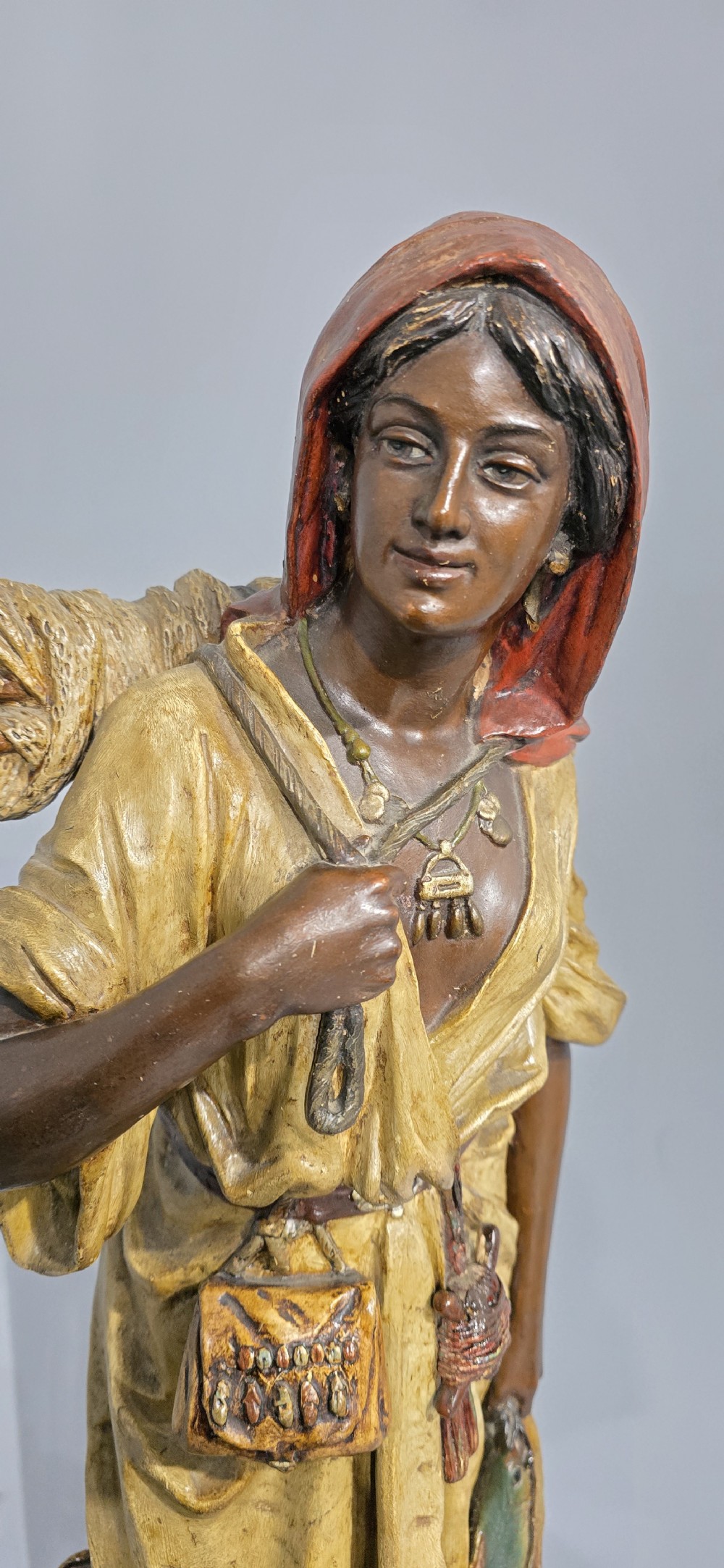 A polychrome terracotta sculpture depicting a standing woman dressed as a fisher girl carrying a basket on her back and holding fish. View V