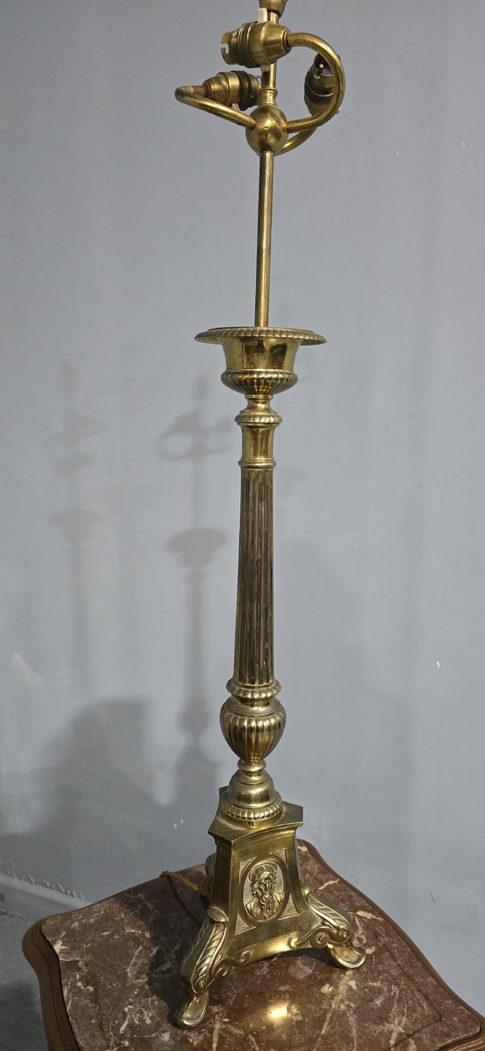 A pair of tall cast brass candlestick table lamps featuring fluted columns, relief portrait medallions on triform bases, and multi-bulb electrical fittings at the top. View IV
