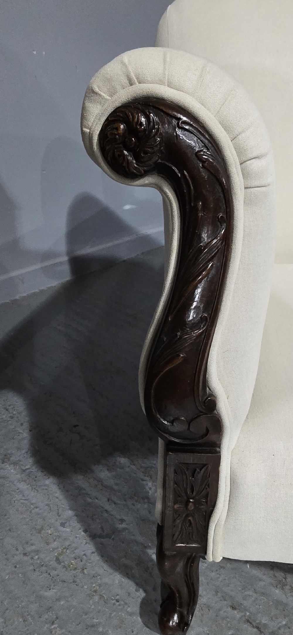 A Victorian two-seater sofa upholstered in plain cream fabric featuring an arched back, rolled padded arms, and dark carved mahogany front legs. View III