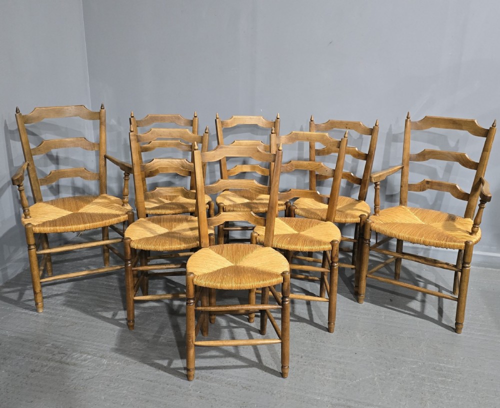 A set of eight French country wooden dining chairs featuring wavy ladderback rails and natural woven rush seats.