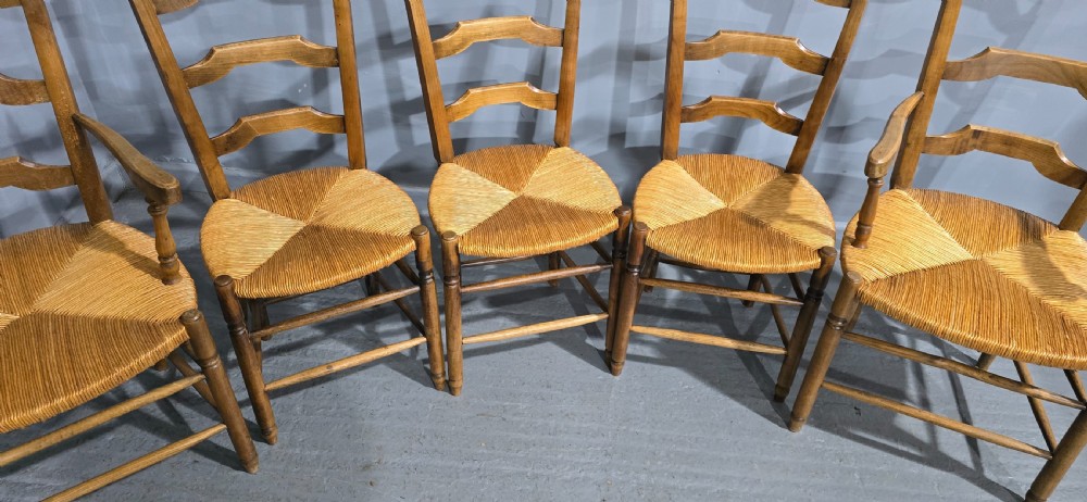 A set of eight French country wooden dining chairs featuring wavy ladderback rails and natural woven rush seats. View V