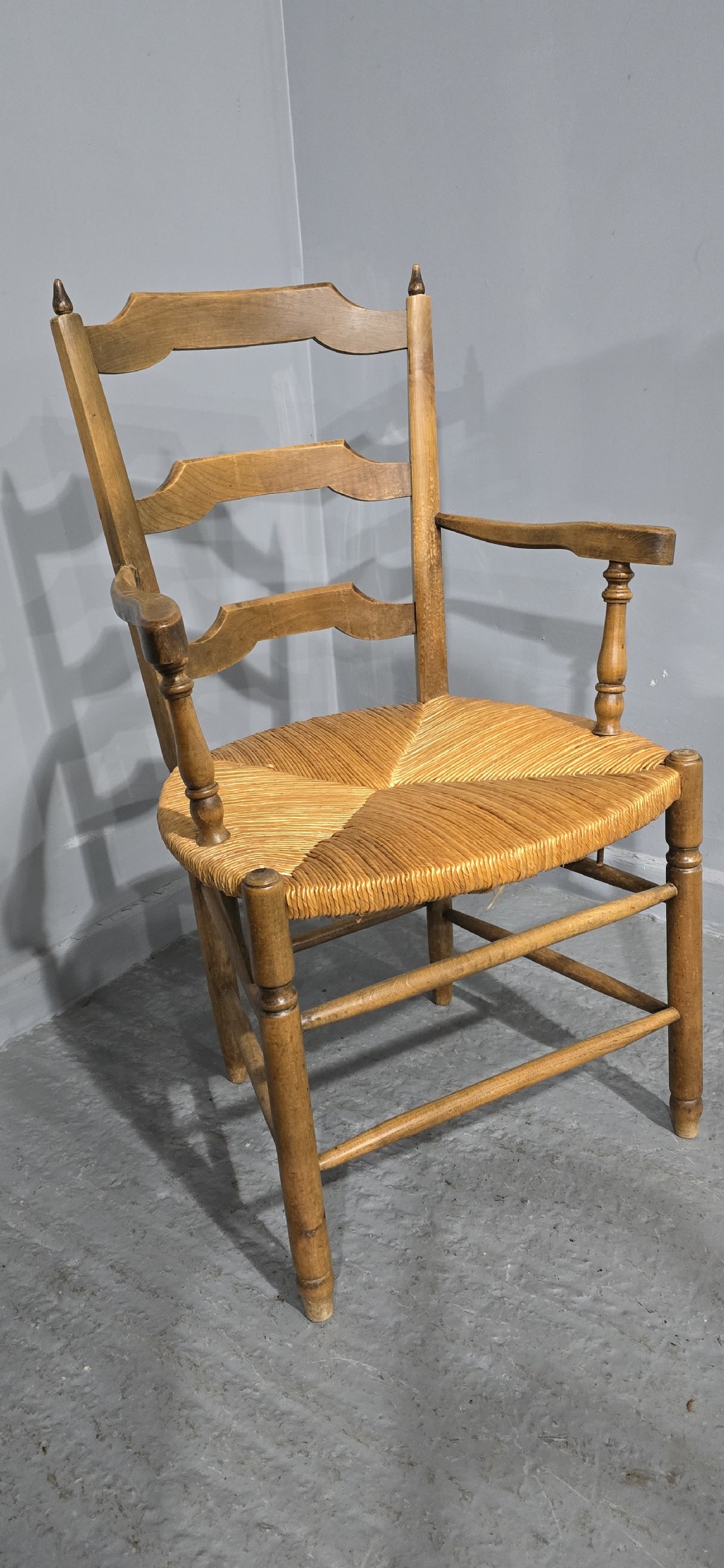 A set of eight French country wooden dining chairs featuring wavy ladderback rails and natural woven rush seats. View VII