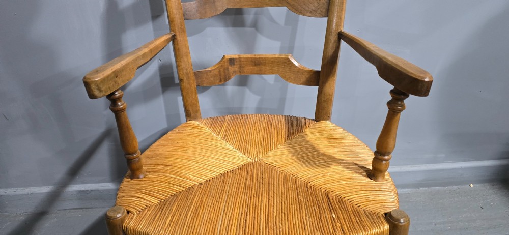 A set of eight French country wooden dining chairs featuring wavy ladderback rails and natural woven rush seats. View VIII