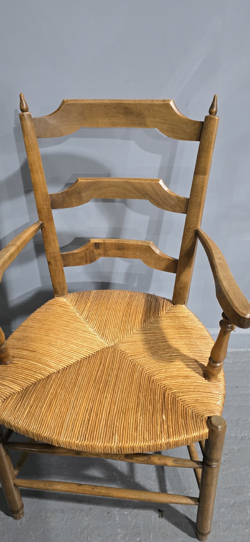 A set of eight French country wooden dining chairs featuring wavy ladderback rails and natural woven rush seats. View IX