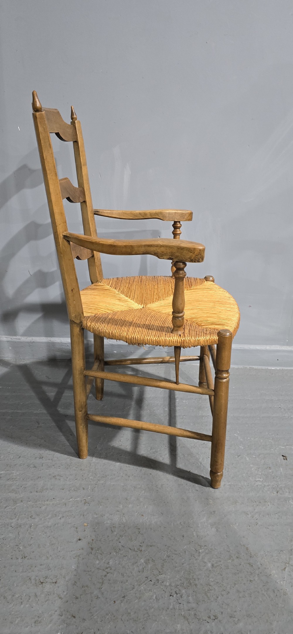A set of eight French country wooden dining chairs featuring wavy ladderback rails and natural woven rush seats. View X