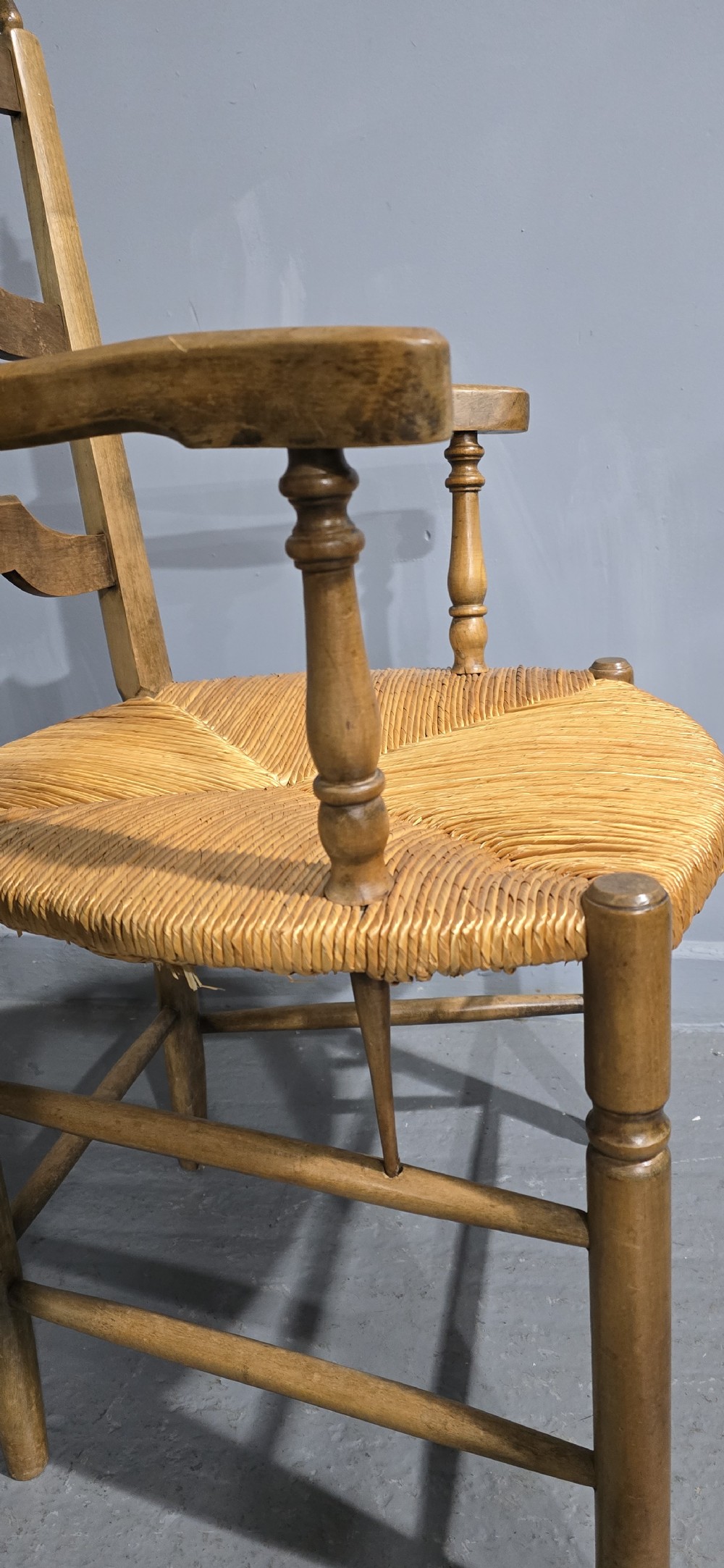 A set of eight French country wooden dining chairs featuring wavy ladderback rails and natural woven rush seats. View XI