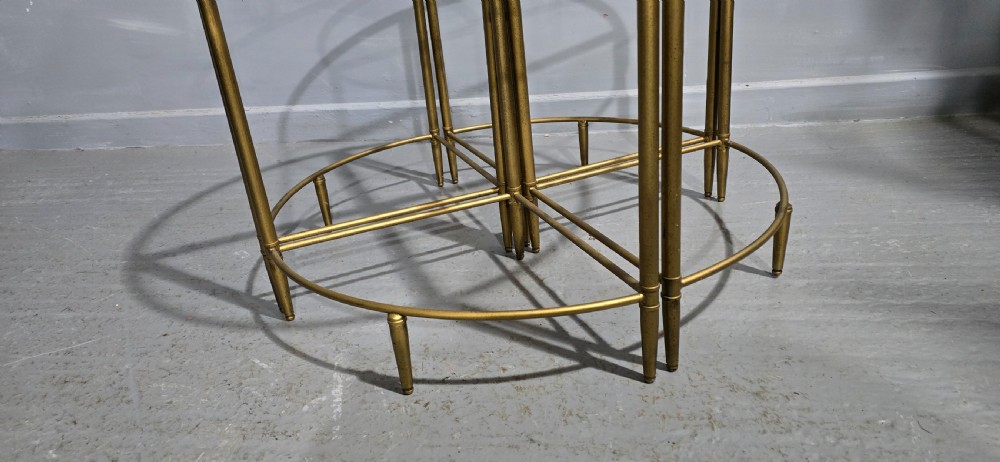 A set of four quadrant-shaped gold brass tables with glass tops arranged together to form a single circular surface. View V