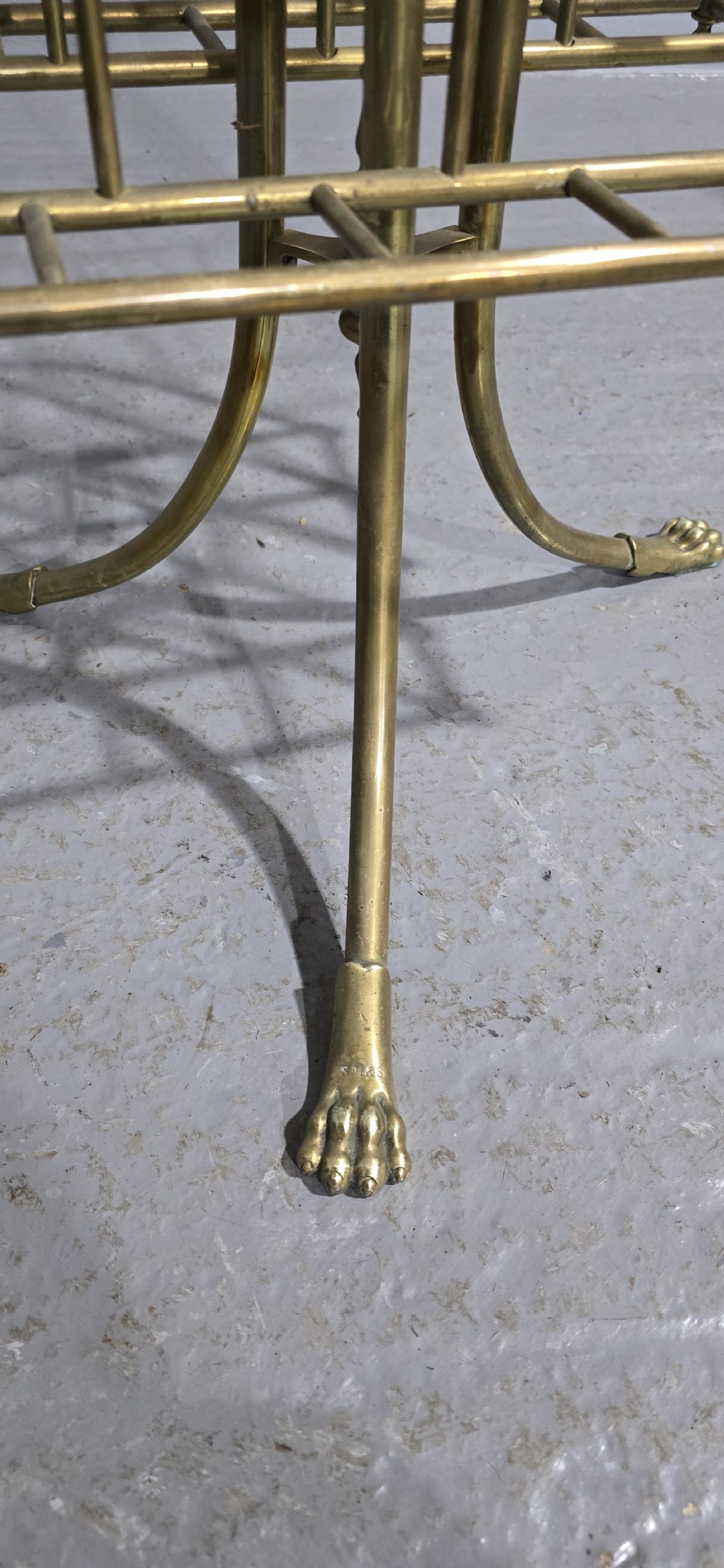 A Victorian brass revolving magazine stand featuring a wireframe rack with shaped dividers, supported on a tripod base with paw feet. View III