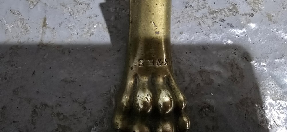 A Victorian brass revolving magazine stand featuring a wireframe rack with shaped dividers, supported on a tripod base with paw feet. View VII