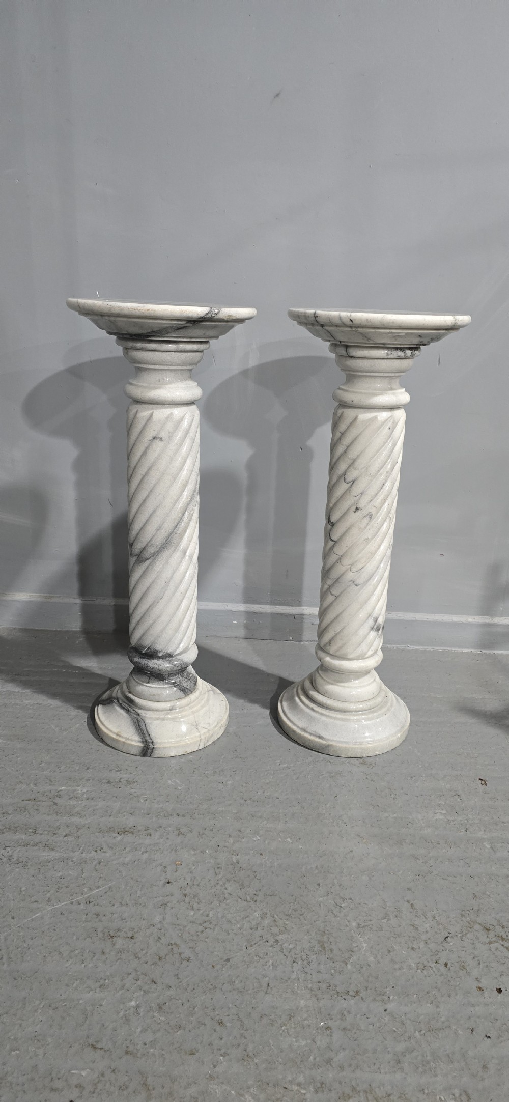 A pair of carved white and grey variegated marble pedestals with spiral shafts, circular capitals, and stepped moulded bases. View II