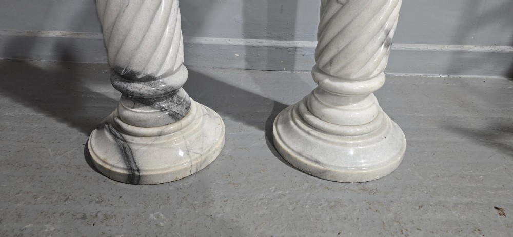 A pair of carved white and grey variegated marble pedestals with spiral shafts, circular capitals, and stepped moulded bases. View V