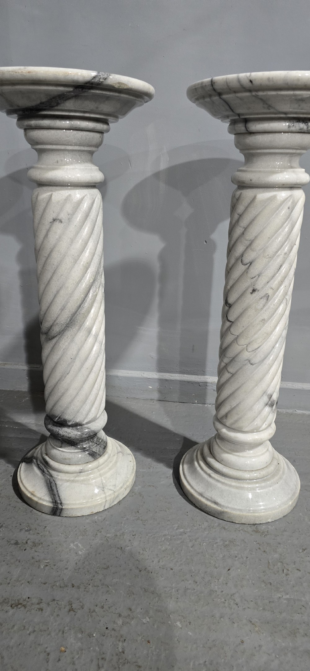 A pair of carved white and grey variegated marble pedestals with spiral shafts, circular capitals, and stepped moulded bases. View VI