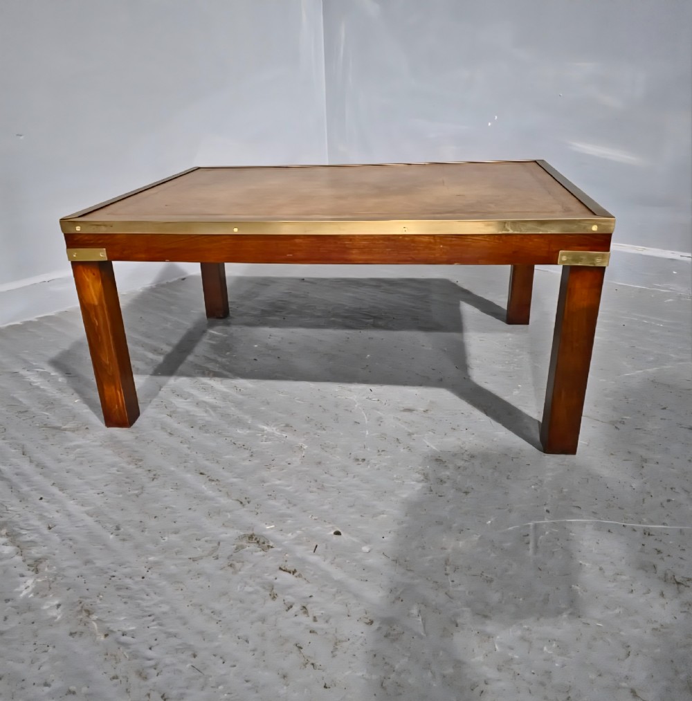 A low rectangular mahogany coffee table featuring a leather inset top bordered by brass strapping and brass corner brackets. View III