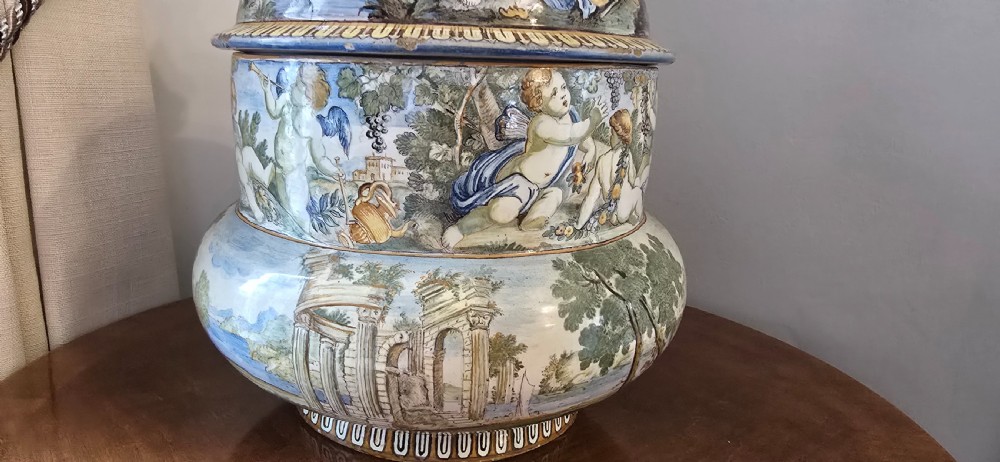 An 18th-century Italian tin-glazed earthenware lidded jar decorated with painted classical landscapes, cherubs, and architectural ruins. View II
