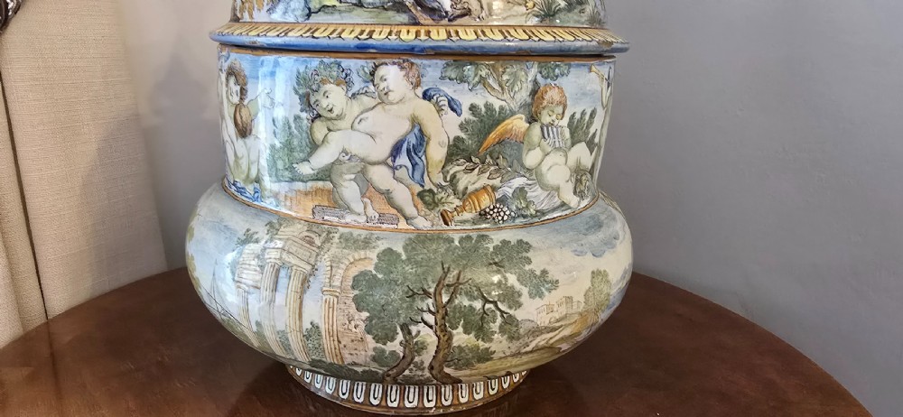 An 18th-century Italian tin-glazed earthenware lidded jar decorated with painted classical landscapes, cherubs, and architectural ruins. View VIII
