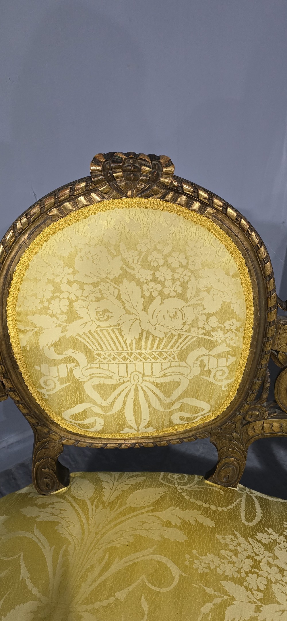 An antique French Louis XVI style giltwood two-seat sofa with twin oval medallion backrests, a central carved lyre motif, fluted legs, and yellow silk damask upholstery. View VI