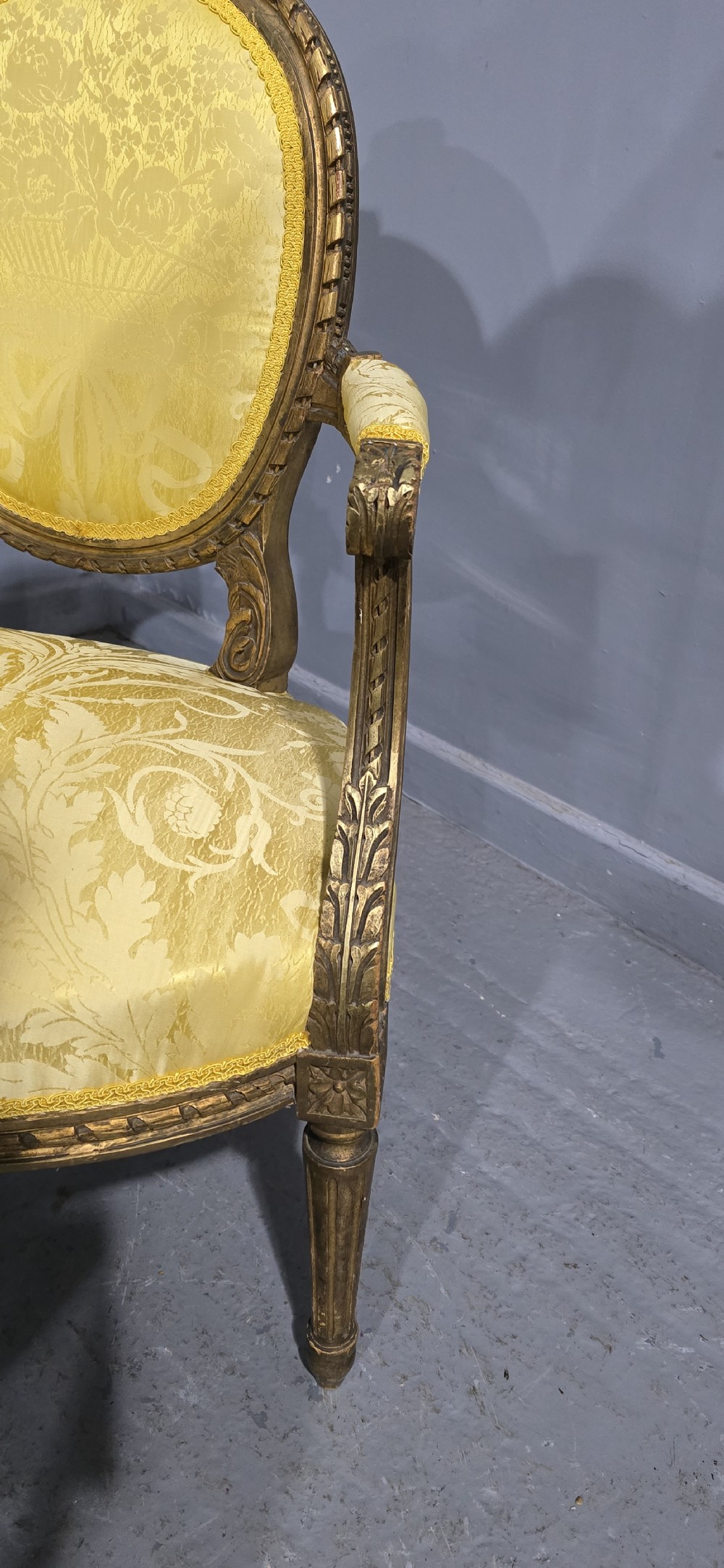 An antique French Louis XVI style giltwood two-seat sofa with twin oval medallion backrests, a central carved lyre motif, fluted legs, and yellow silk damask upholstery. View IX