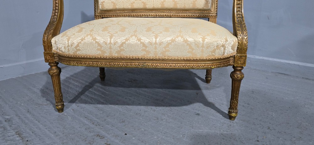 A French Louis XVI style two-seat settee featuring a carved giltwood frame with fluted legs and cream floral damask upholstery. View III