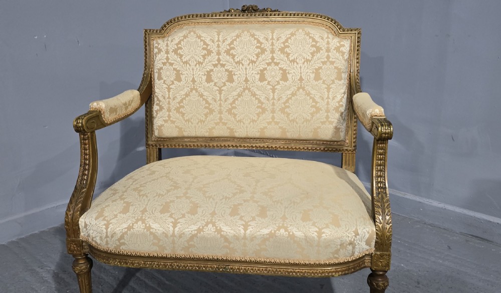 A French Louis XVI style two-seat settee featuring a carved giltwood frame with fluted legs and cream floral damask upholstery. View IV