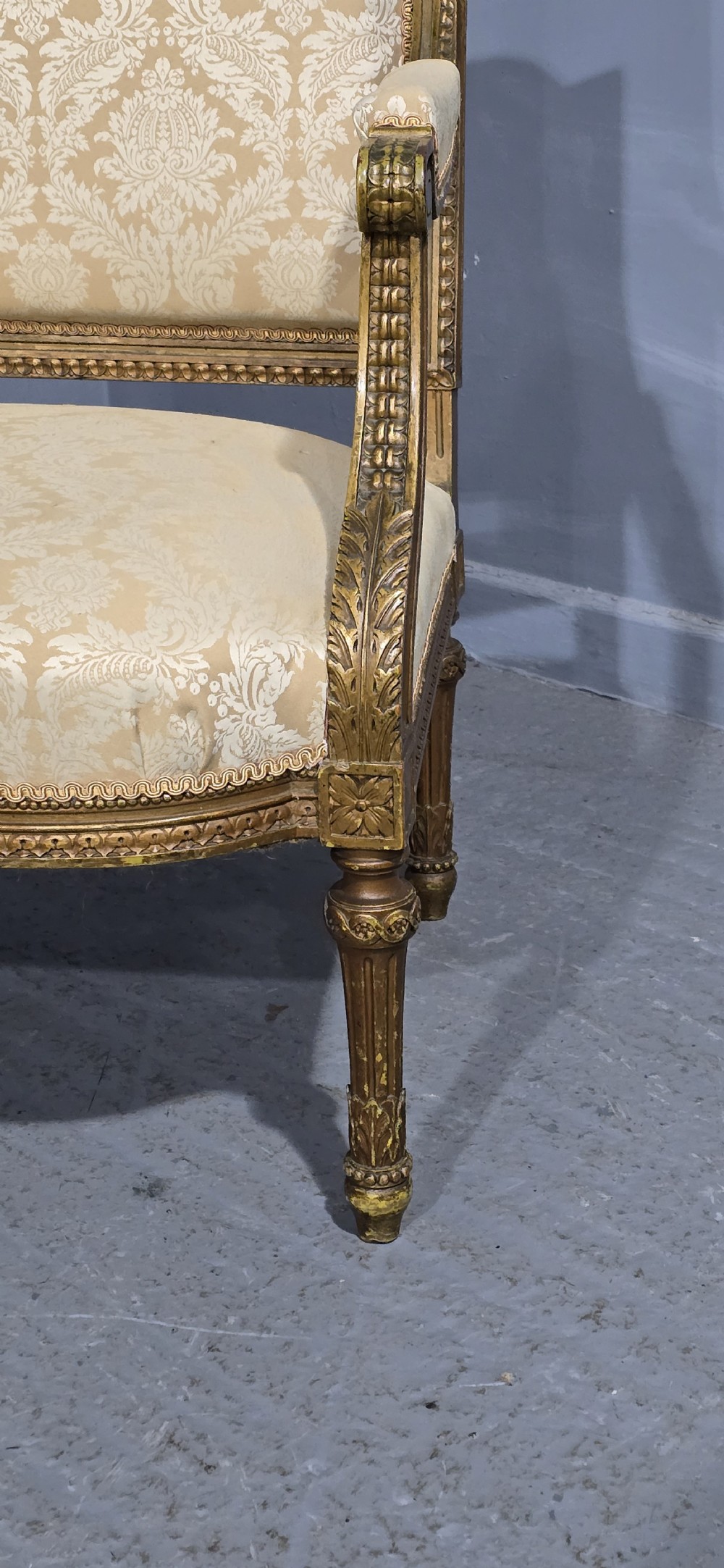 A French Louis XVI style two-seat settee featuring a carved giltwood frame with fluted legs and cream floral damask upholstery. View V