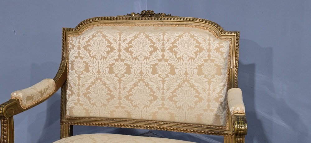 A French Louis XVI style two-seat settee featuring a carved giltwood frame with fluted legs and cream floral damask upholstery. View VII