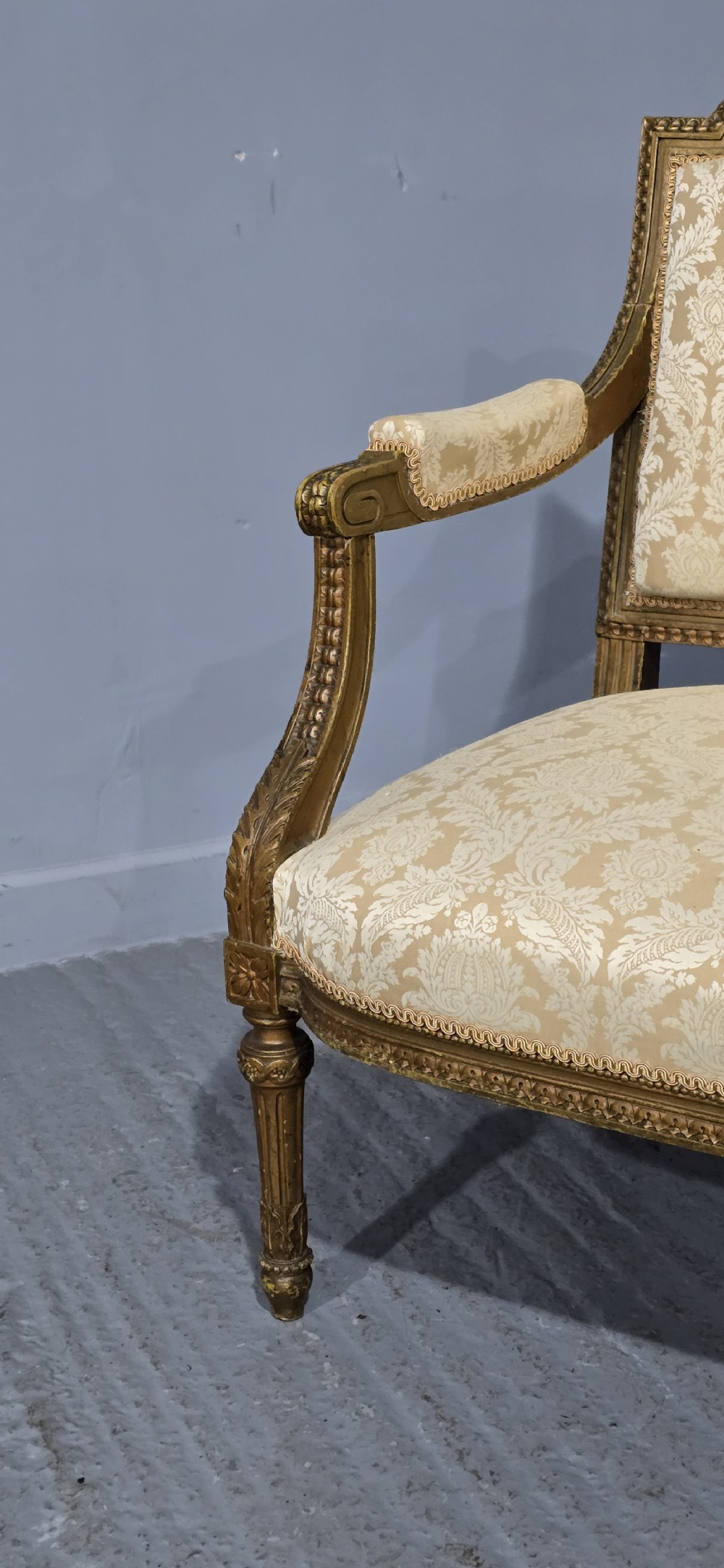 A French Louis XVI style two-seat settee featuring a carved giltwood frame with fluted legs and cream floral damask upholstery. View VIII