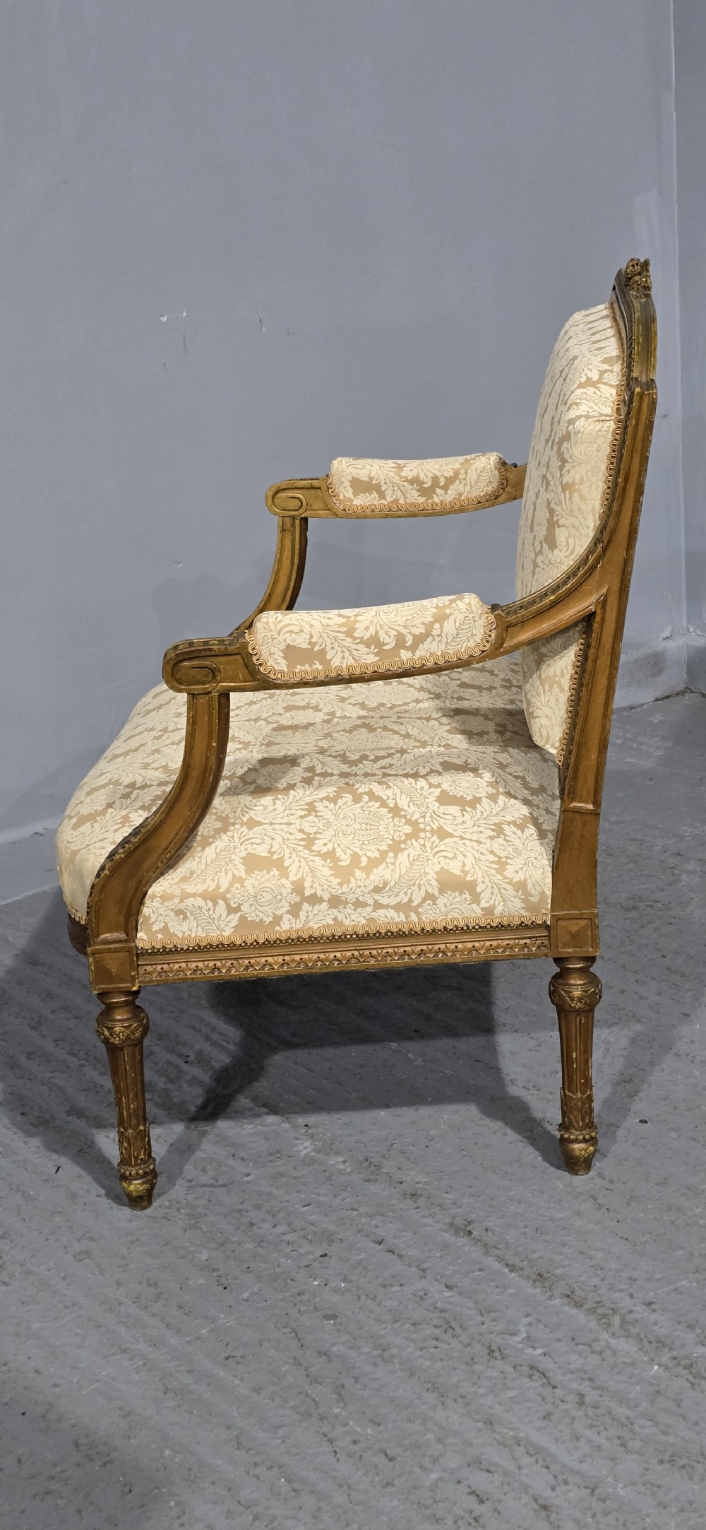 A French Louis XVI style two-seat settee featuring a carved giltwood frame with fluted legs and cream floral damask upholstery. View IX