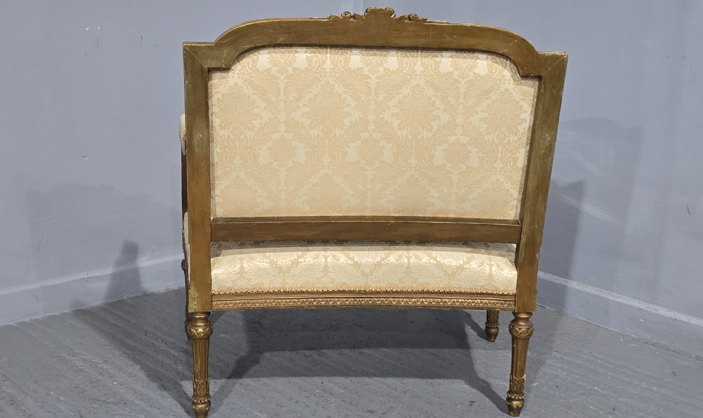 A French Louis XVI style two-seat settee featuring a carved giltwood frame with fluted legs and cream floral damask upholstery. View X