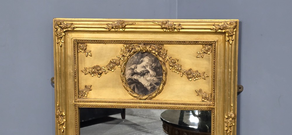 An antique French giltwood trumeau mirror featuring a tall rectangular frame topped with a carved oval painted portrait inset and floral garlands. View III