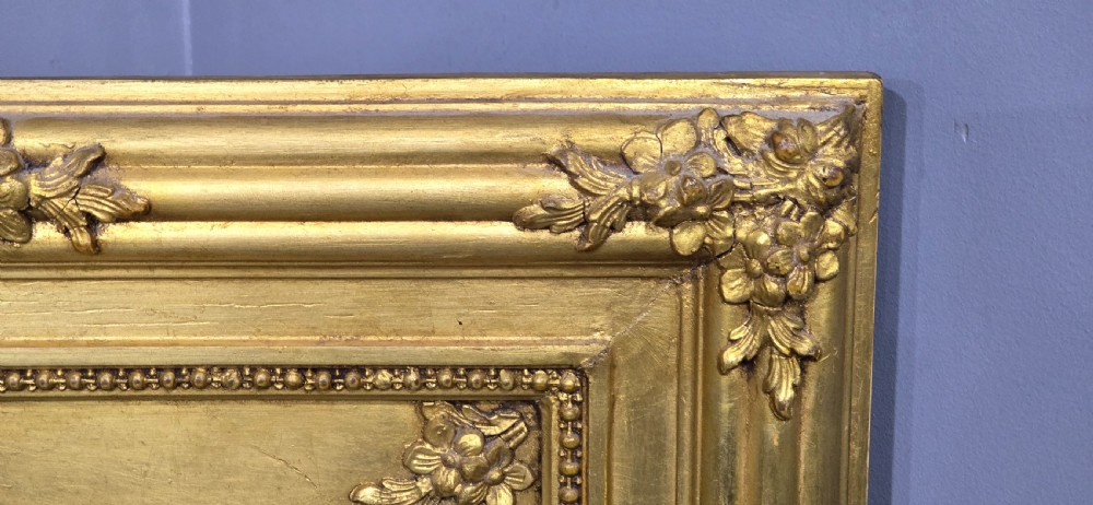 An antique French giltwood trumeau mirror featuring a tall rectangular frame topped with a carved oval painted portrait inset and floral garlands. View VIII