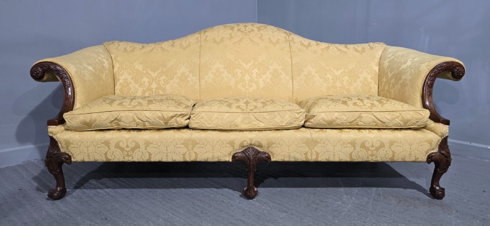 A camelback sofa upholstered in patterned yellow damask fabric with carved mahogany scroll arms and cabriole legs terminating in ball and claw feet. View VI