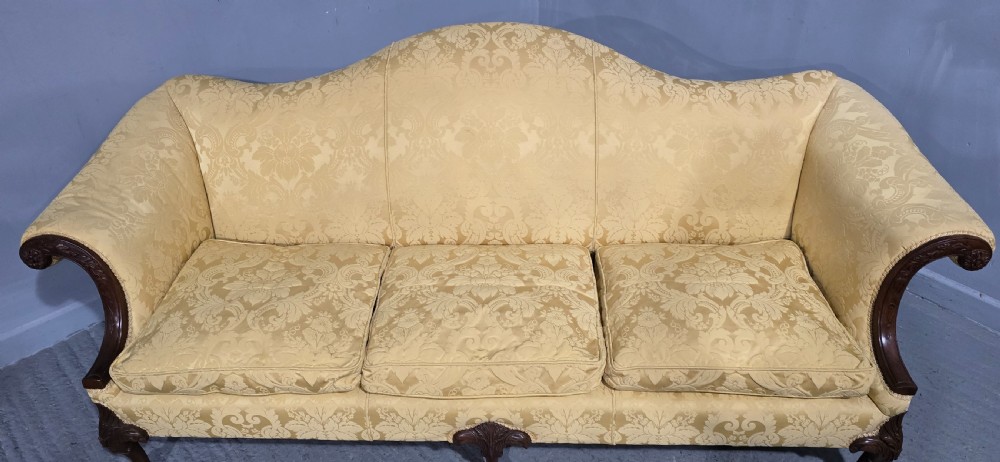A camelback sofa upholstered in patterned yellow damask fabric with carved mahogany scroll arms and cabriole legs terminating in ball and claw feet. View VII