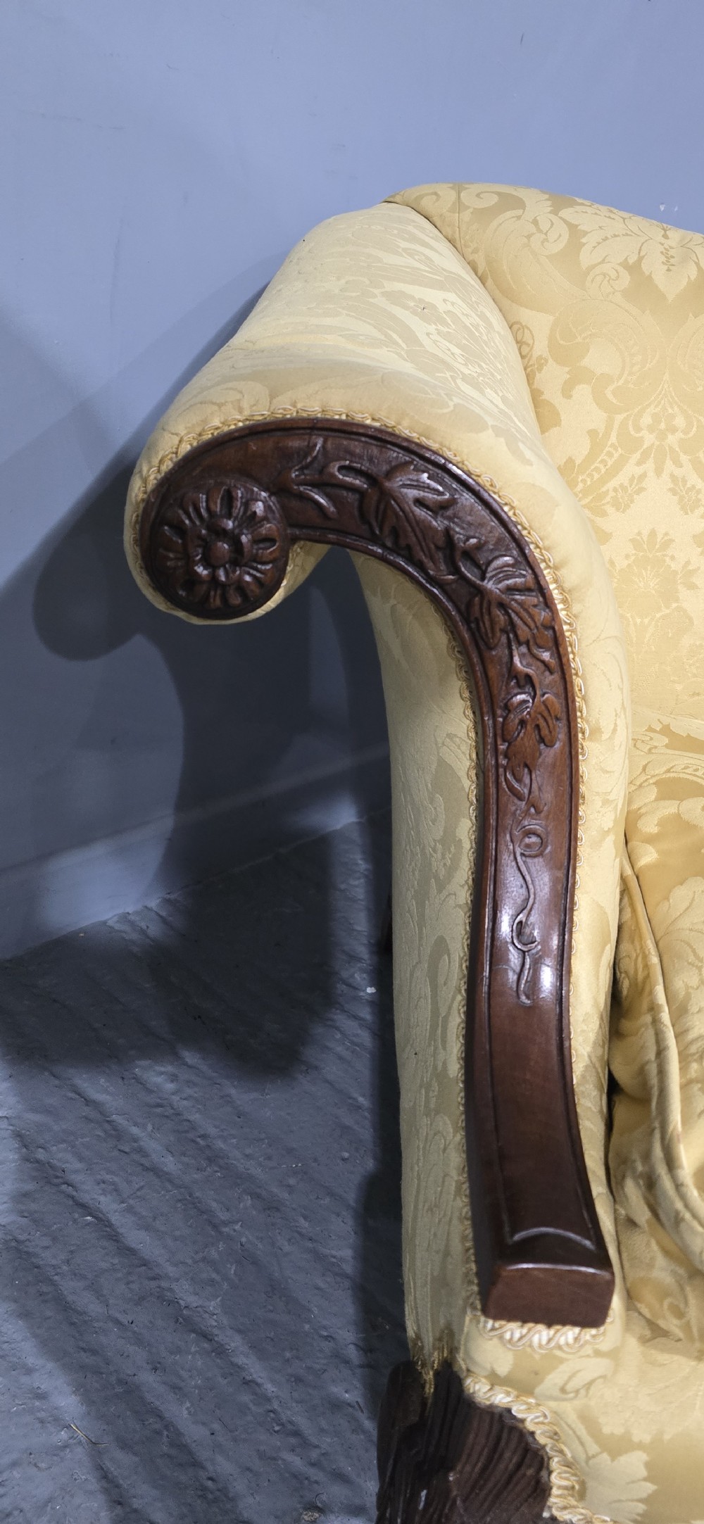 A camelback sofa upholstered in patterned yellow damask fabric with carved mahogany scroll arms and cabriole legs terminating in ball and claw feet. View VIII
