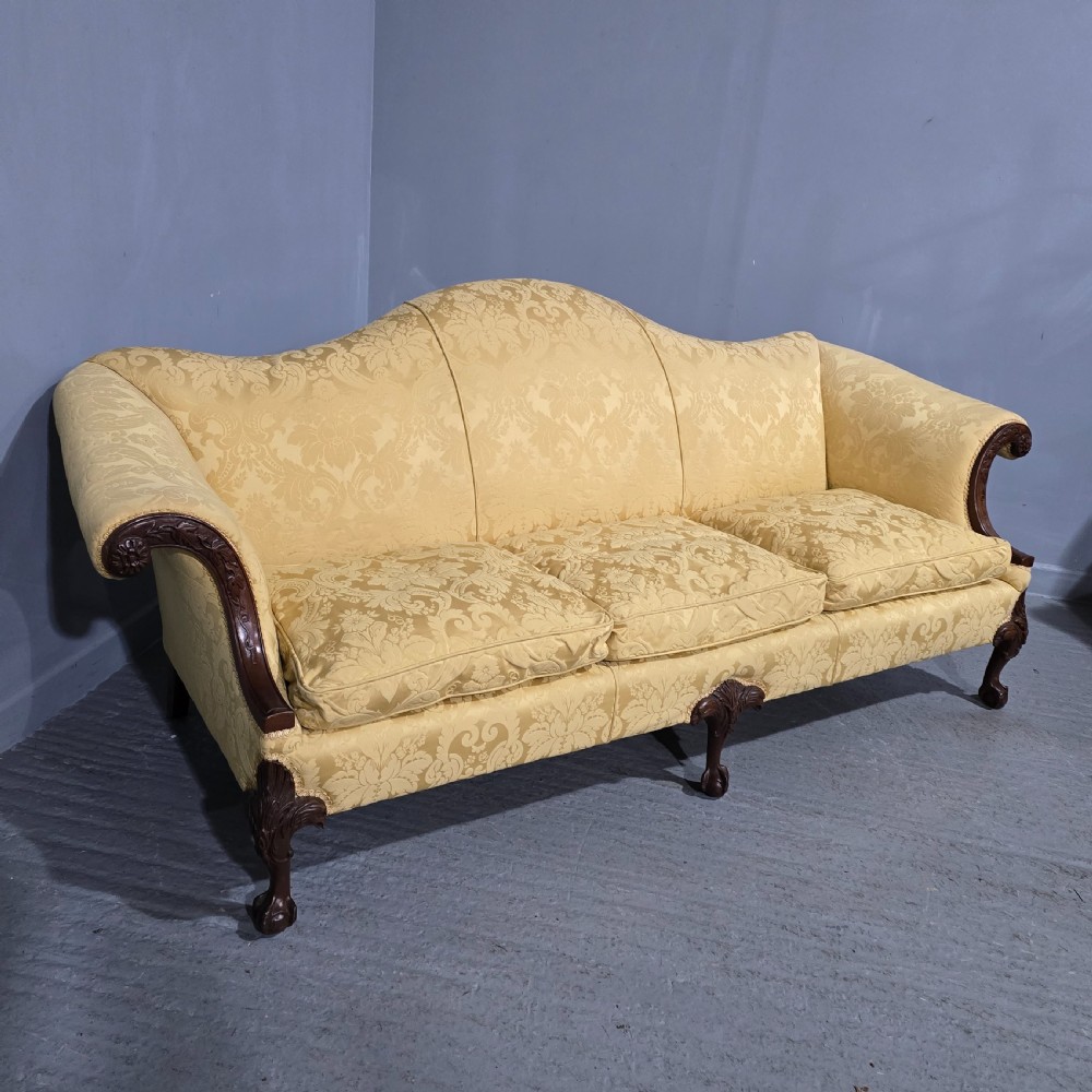 A camelback sofa upholstered in patterned yellow damask fabric with carved mahogany scroll arms and cabriole legs terminating in ball and claw feet. View XII
