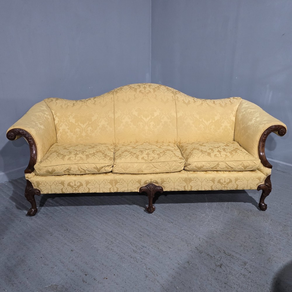 A camelback sofa upholstered in patterned yellow damask fabric with carved mahogany scroll arms and cabriole legs terminating in ball and claw feet. View XIII