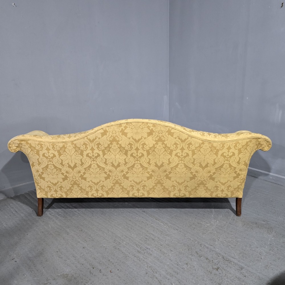 A camelback sofa upholstered in patterned yellow damask fabric with carved mahogany scroll arms and cabriole legs terminating in ball and claw feet. View XIV