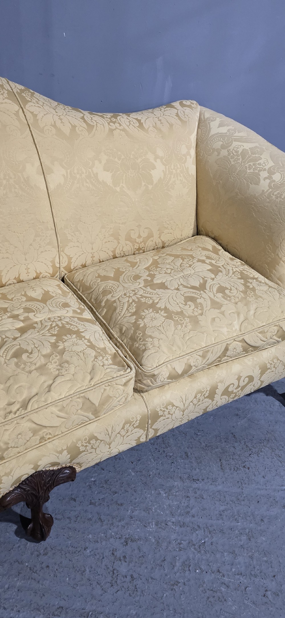 A camelback sofa upholstered in patterned yellow damask fabric with carved mahogany scroll arms and cabriole legs terminating in ball and claw feet. View XVI