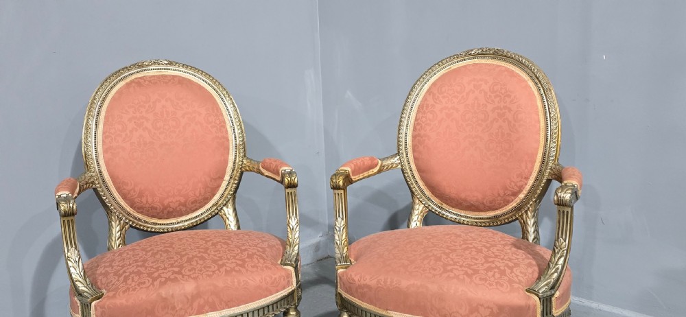 A pair of French Louis XVI style elbow chairs featuring silver gilt carved frames with oval backs, fluted legs, and pink patterned upholstery. View IV