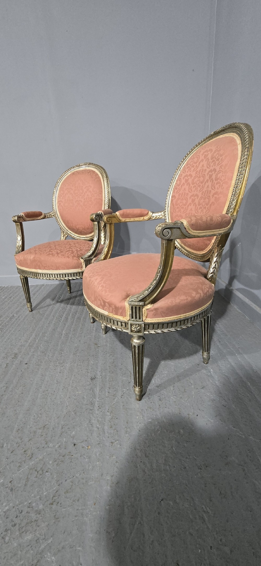 A pair of French Louis XVI style elbow chairs featuring silver gilt carved frames with oval backs, fluted legs, and pink patterned upholstery. View VII
