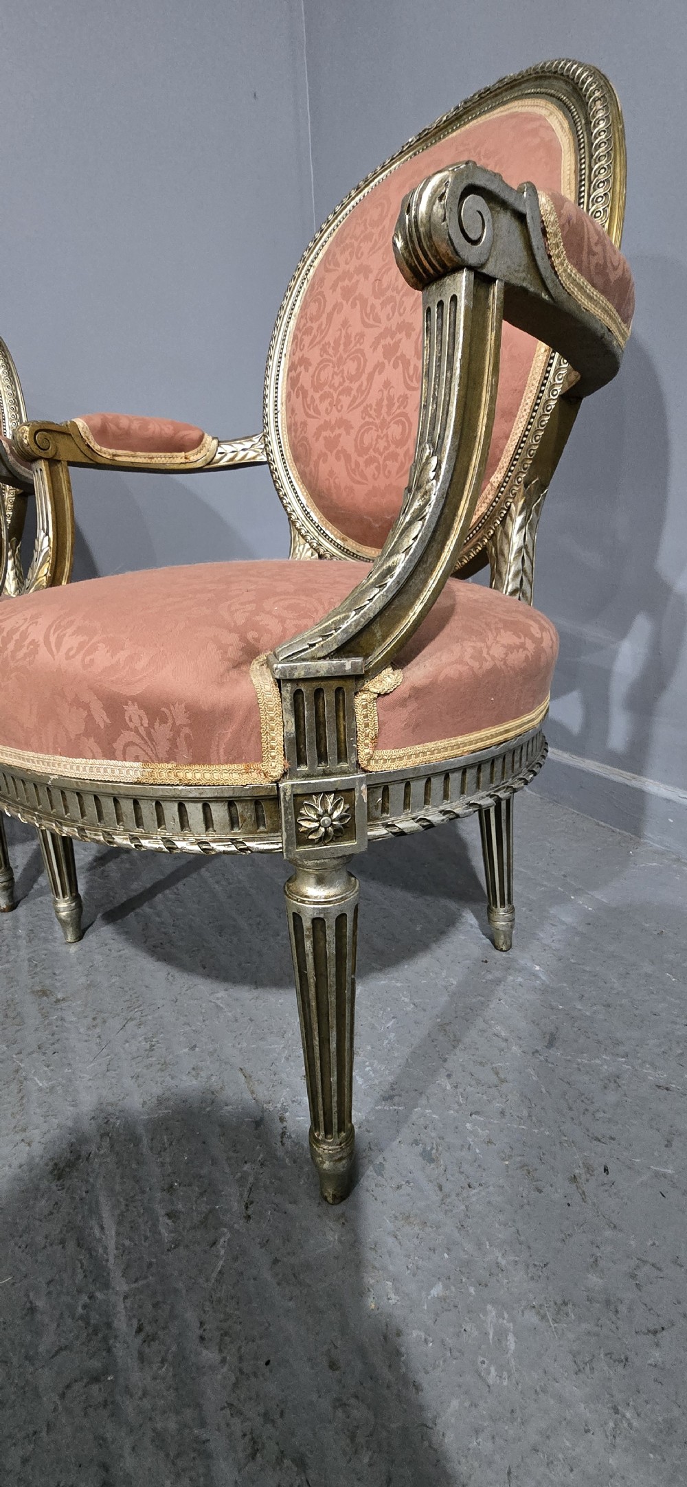 A pair of French Louis XVI style elbow chairs featuring silver gilt carved frames with oval backs, fluted legs, and pink patterned upholstery. View VIII