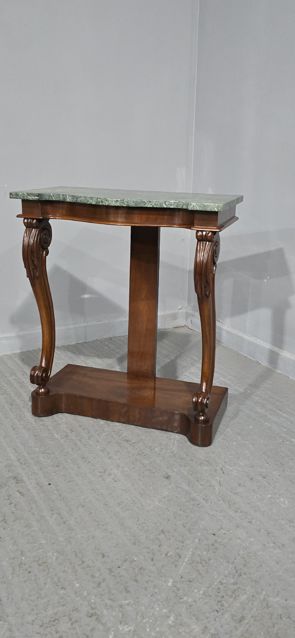 A mahogany console table featuring a green marble top supported by carved scrolled front legs on a plinth base. View II