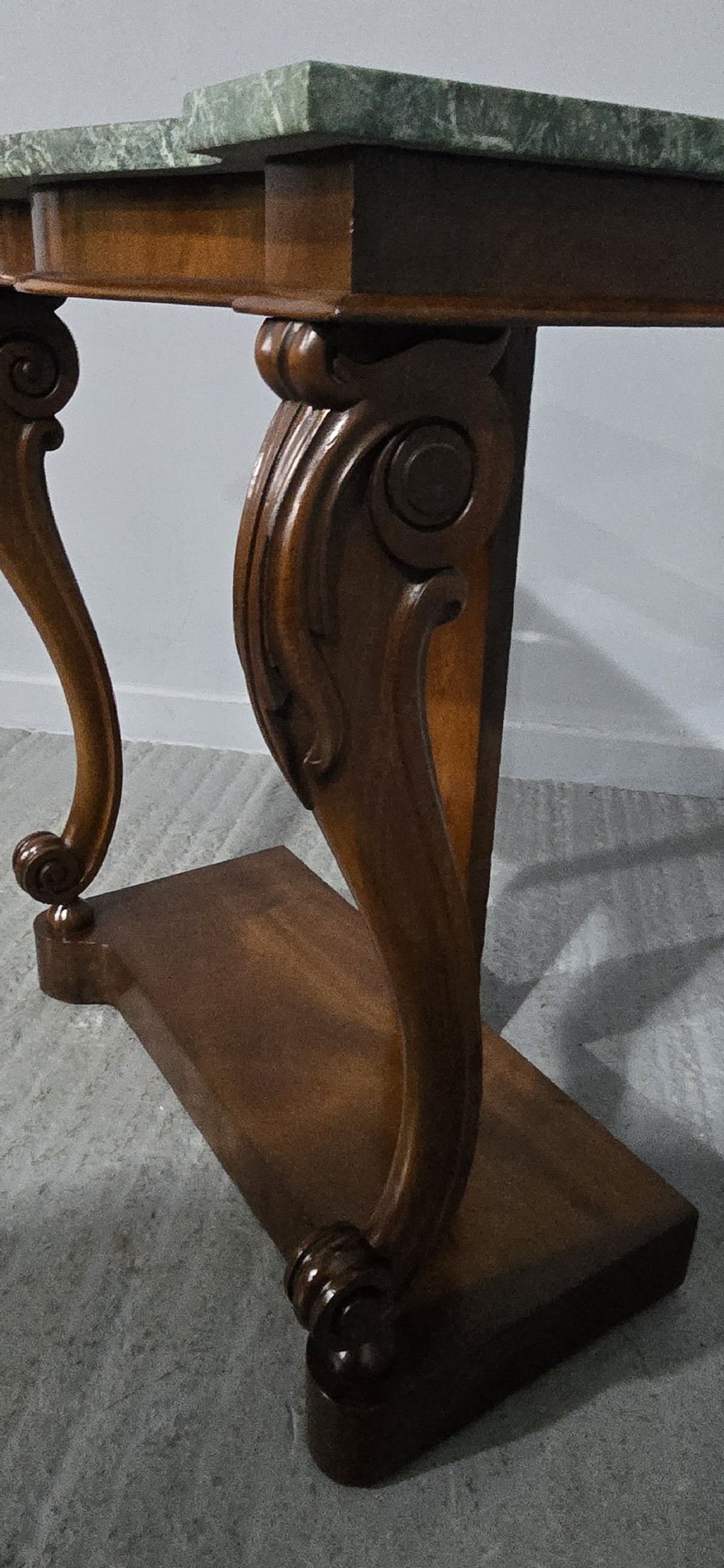 A mahogany console table featuring a green marble top supported by carved scrolled front legs on a plinth base. View IV