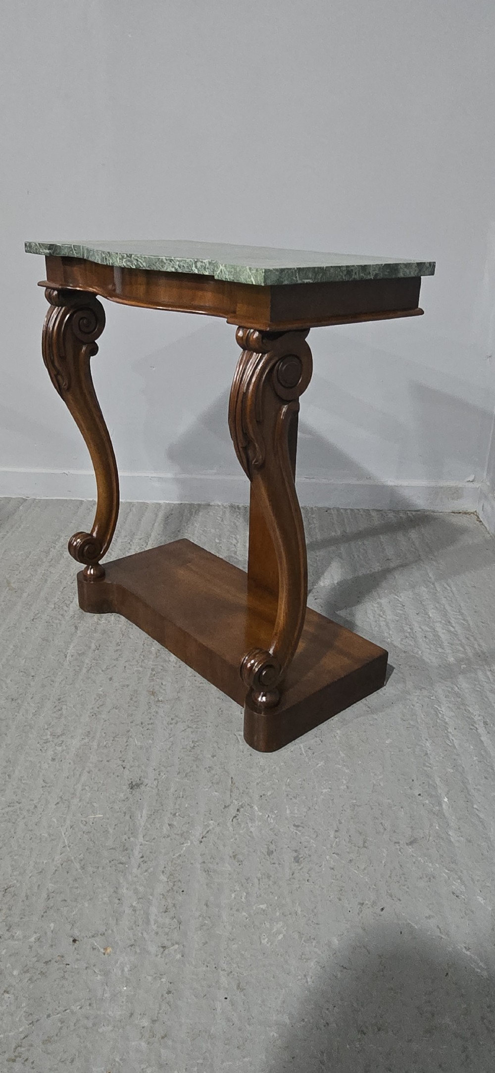 A mahogany console table featuring a green marble top supported by carved scrolled front legs on a plinth base. View V